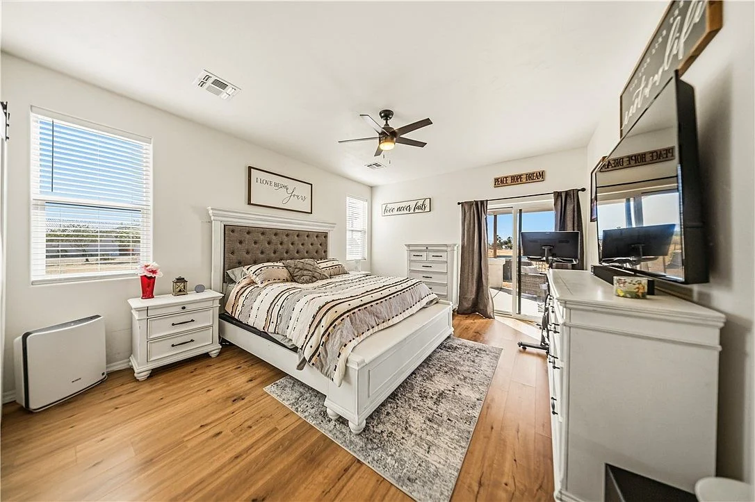 Bedroom with windows, a ceiling fan and the home's existing furnishings